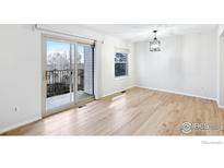 Bright living room featuring hardwood floors, a modern light fixture and sliding door access to outdoor balcony at 1383 W 88Th Ave # 307, Thornton, CO 80260
