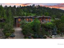 Stunning mountain home with lush landscaping and stone accents nestled in a serene forest setting at 1420 Sierra Dr, Boulder, CO 80302
