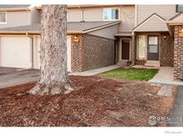Townhome exterior with brick accents, neutral siding, front yard landscaping and shade tree at 1634 Centaur Cir, Lafayette, CO 80026