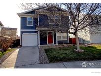 Charming two-story home featuring a well-manicured lawn and a one car garage, painted in navy blue and white at 10591 Forester Pl, Longmont, CO 80504