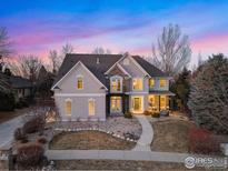 Stunning two-story home featuring a stone facade, balcony, and landscaped front yard under a colorful dusk sky at 1321 Onyx Cir, Longmont, CO 80504