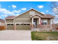 Charming home with a three-car garage and inviting front porch with an American flag at 16024 Columbine St, Thornton, CO 80602