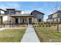 Charming two-story home featuring a stone facade, inviting front porch, and well-manicured lawn at 174 High Point Dr, Longmont, CO 80504