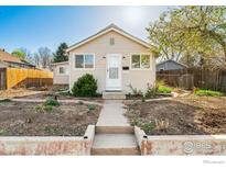 Charming single-story home with light beige siding, a concrete walkway, and a small well kept yard and flowerbeds at 6058 S Hill St, Littleton, CO 80120