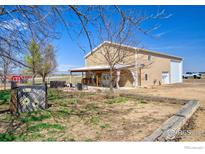 Tan barndominium with covered patio featuring outdoor seating, a manicured yard and a clear blue sky at 6251 County Road 20, Longmont, CO 80504