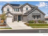 Inviting two-story home featuring a stone accented garage, solar panels, and a well-maintained front yard at 16335 Spanish Peak Way, Broomfield, CO 80023