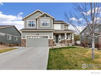Charming two-story home featuring a two-car garage, stone accents, and well-maintained lawn at 16848 Weber Way, Mead, CO 80542