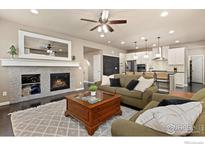 Inviting living room featuring a fireplace, ceiling fan, and seamlessly connecting to an open kitchen concept at 16848 Weber Way, Mead, CO 80542