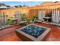 Cozy backyard with Adirondack chairs and a square fire pit with blue stones, perfect for outdoor entertaining at 226 Ole Bessie Dr, Berthoud, CO 80513
