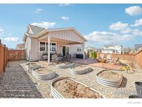 Landscaped backyard with vegetable garden, covered patio, seating area, and inviting fire pit at 226 Ole Bessie Dr, Berthoud, CO 80513