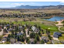 Stunning aerial view of a home nestled among trees, overlooking a lake, golf course, and mountain range at 4207 Birdie Ct, Longmont, CO 80503