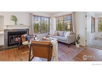 Cozy living room with fireplace, wood floors, and large windows at 4819 White Rock Cir # C, Boulder, CO 80301