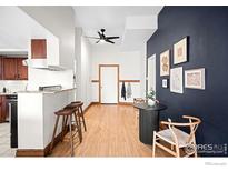 Bright living room featuring wood floors, dining area and eye-catching blue accent wall at 2351 Federal Blvd # 102, Denver, CO 80211