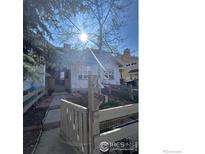 Charming home with a fenced yard and a welcoming entrance; sunlight filters through the bare branches of a mature tree at 2569 Stonewall Ln, Lafayette, CO 80026