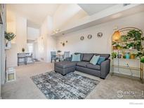 Bright living room featuring a gray sectional sofa, modern decor, and neutral carpet at 3235 S Walden Ct # E, Aurora, CO 80013