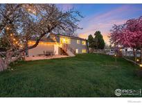 Relaxing backyard with lush lawn, patio dining, and flowering trees at twilight at 4547 Ashfield Dr, Boulder, CO 80301