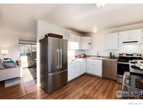 Bright kitchen features stainless steel appliances, white cabinetry, and hardwood floors at 4547 Ashfield Dr, Boulder, CO 80301