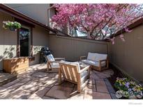 Stone patio featuring outdoor seating and a grill, shaded by a blooming tree creating a relaxing outdoor oasis at 4654 Greenbriar Ct, Boulder, CO 80305
