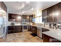 Modern kitchen with granite countertops, stainless steel appliances, and beautiful brown cabinets at 10679 Union Way, Broomfield, CO 80021