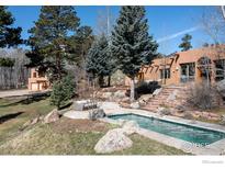 Exterior view of custom home featuring an in-ground pool, stone patio and mature landscaping at 136 Old Post Office Rd, Boulder, CO 80302