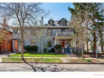 Charming home showcasing a front porch, balcony, manicured lawn, and mature trees at 1373 N Franklin St # 1, Denver, CO 80218