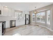 Bright kitchen with stainless steel appliances, white cabinetry and modern light fixture at 16457 Lafayette St, Thornton, CO 80602