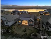 Breathtaking aerial view of a modern home with waterfront and mountain views at sunset at 2882 Heron Lakes Pkwy, Berthoud, CO 80513