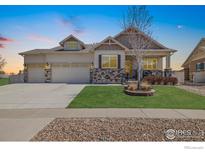 Charming home with a three-car garage, stone accents, manicured lawn, and welcoming front porch at 8962 Foxfire St, Firestone, CO 80504