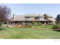 Expansive home featuring covered porches, beautiful landscaping, stone accents and mature trees at 9402 Crystal Ln, Longmont, CO 80503