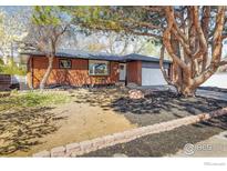Charming brick home with a well-manicured front yard and mature trees at 1153 Atwood St, Longmont, CO 80501