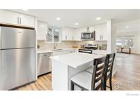 Bright kitchen with white cabinets, stainless steel appliances, and a breakfast bar at 11833 W Marlowe Pl, Morrison, CO 80465