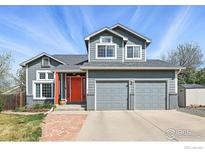 Charming two-story home featuring a two-car garage, gray siding, bright orange front door and well-manicured lawn at 1528 Alpine St, Longmont, CO 80504