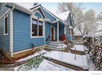 Charming blue home featuring a covered front entrance with a red-railed stairway and snow-covered landscaping at 1605 17Th St, Boulder, CO 80302