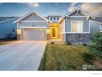 Charming single-Gathering home with gray siding, stone accents, a well-manicured lawn, and an attached two-car garage at 452 Wagon Bend Rd, Berthoud, CO 80513
