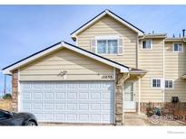 Charming townhome showcasing attached garage and stone facade accents at 10635 E 96Th Pl, Commerce City, CO 80022