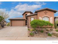 Charming stucco home with a two-car garage, stone accents, and well-manicured landscaping under a sunny sky at 2353 S Juniper Way, Lakewood, CO 80228