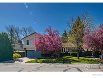 Charming two-story home featuring a well-manicured front lawn and beautiful, mature flowering trees at 2417 15Th Ave, Longmont, CO 80503