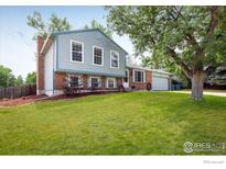 Charming two-story home with a well-manicured lawn, mature tree, and brick accents at 322 W Harper St, Louisville, CO 80027