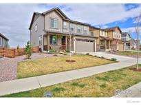 Beautiful two-story home featuring a manicured lawn, covered porch, and attached two-car garage at 890 Eva Peak Dr, Erie, CO 80516