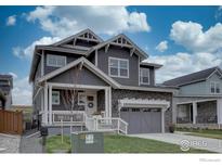 Charming two-story home featuring a gray exterior, stone accents, well-manicured lawn, and attached two-car garage at 1031 Turnberry Cir, Louisville, CO 80027