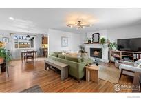 Bright living room featuring hardwood floors, fireplace, and a neutral green sofa at 1527 Sherri Mar St, Longmont, CO 80501