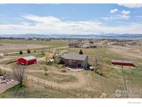 Expansive aerial view of ranch home with mountain views, outbuildings, and mature trees at 1916 W County Road 6, Berthoud, CO 80513