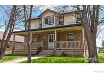 Inviting two-story home featuring a brick facade and a charming front porch at 313 E Iowa Ave, Berthoud, CO 80513