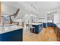 Modern kitchen with a large blue island, stainless steel appliances, hardwood floors, and pendant lighting at 563 Arapahoe Ave, Boulder, CO 80302