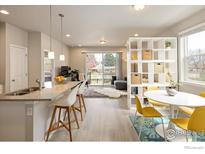 Bright open-concept living and dining area featuring modern decor and a sliding door to an outdoor space at 655 Stonebridge Dr, Longmont, CO 80503