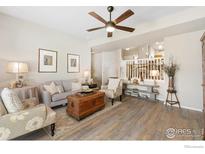 Bright living room with wood floors, ceiling fan, and comfortable seating arrangement at 1453 Woodcock St, Berthoud, CO 80513