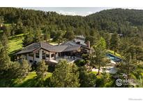 Breathtaking aerial view of a mountain home, pool, and mature trees in a private wooded setting at 1530 Timber Ln, Boulder, CO 80304