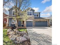 Charming two-story home with a stone facade, well-maintained lawn, and a picturesque stream feature at 1619 Bluefield Ave, Longmont, CO 80504