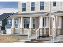 Welcoming front porch with classic columns and stone accents on a charming townhome at 193 Liberty St, Erie, CO 80516