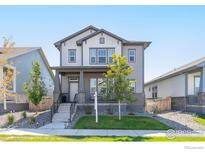 Charming two-story home with gray siding, landscaped yard, and a welcoming front porch at 21574 E 59Th Dr, Aurora, CO 80019